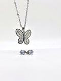 Close-up view of a silver butterfly necklace with crystal accents and matching stud earrings.