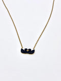 Close-up view of a gold heart pendant necklace with black stone details.