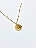 Elegant gold necklace with a round pendant and intricate cut-out pattern.
