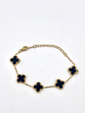 Elegant gold bracelet with black clover-shaped charms for women.